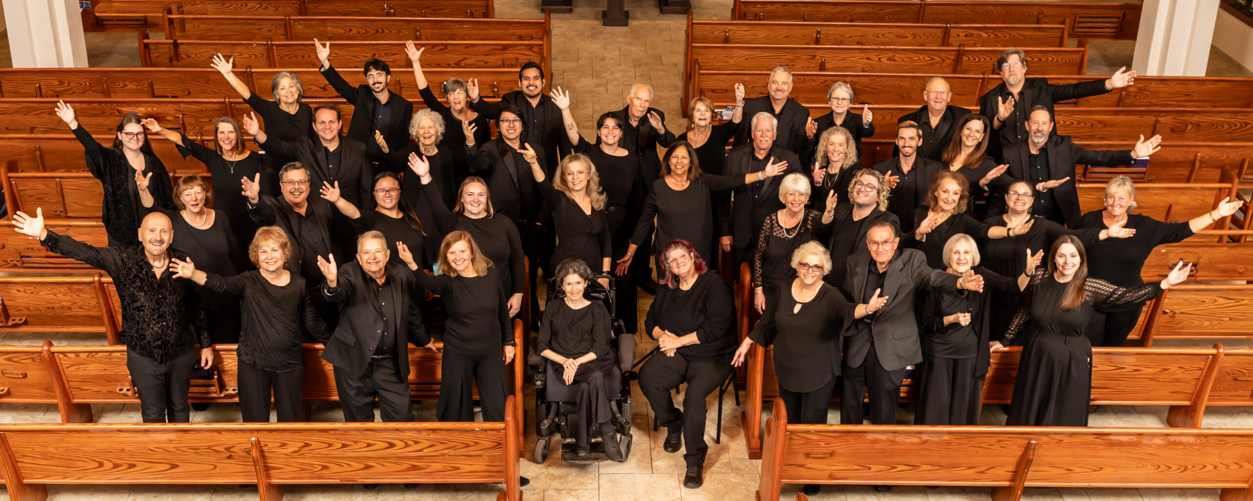 Group photo of Via Nova Chorale with outstretched arms looking up